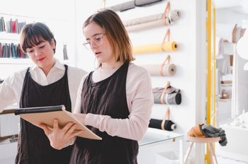Two women looking over clothing design on notepad