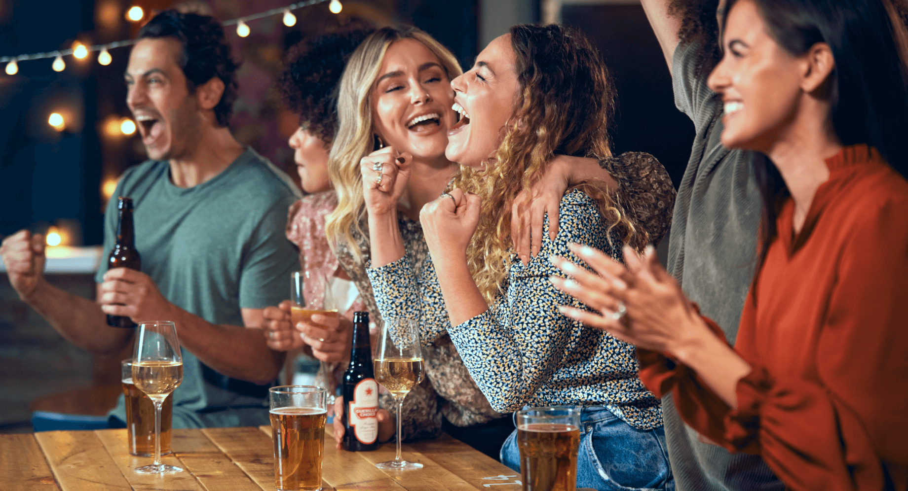 Group of friends drinking in bar and cheering