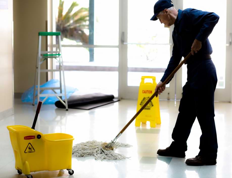 Senior man working as a janitor mopping in building